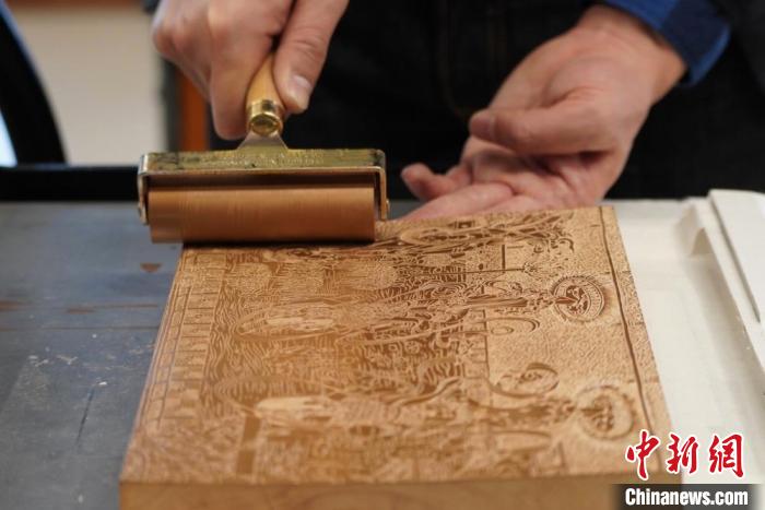 圖為徐晉林工作室工作人員正在給雕好壁畫的版面滾油墨?！【琶赖┰?　攝