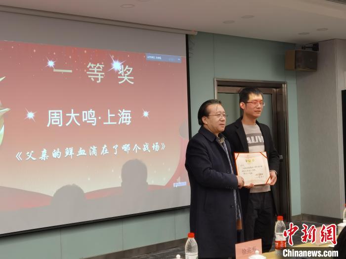 圖為作家、西北師范大學(xué)新聞與傳媒學(xué)院院長(zhǎng)徐兆壽頒發(fā)一等獎(jiǎng)證書(shū)，代領(lǐng)獎(jiǎng)?wù)呱吓_(tái)領(lǐng)獎(jiǎng)?！钅?攝