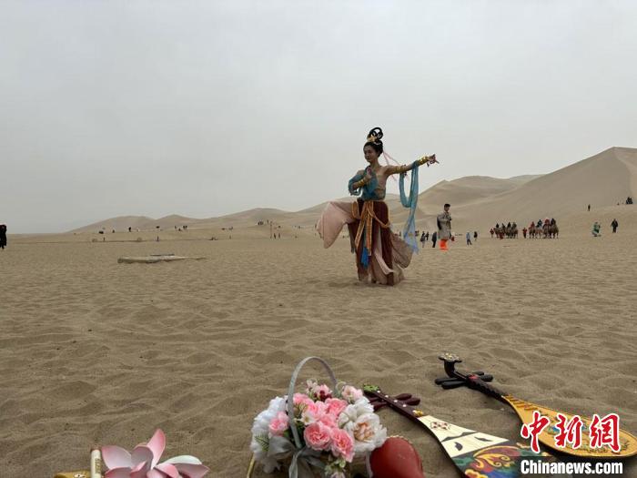 圖為2023年4月底，敦煌大漠“逐舞者”奧楠在鳴沙山月牙泉景區(qū)視頻直播敦煌舞?！●T志軍 攝
