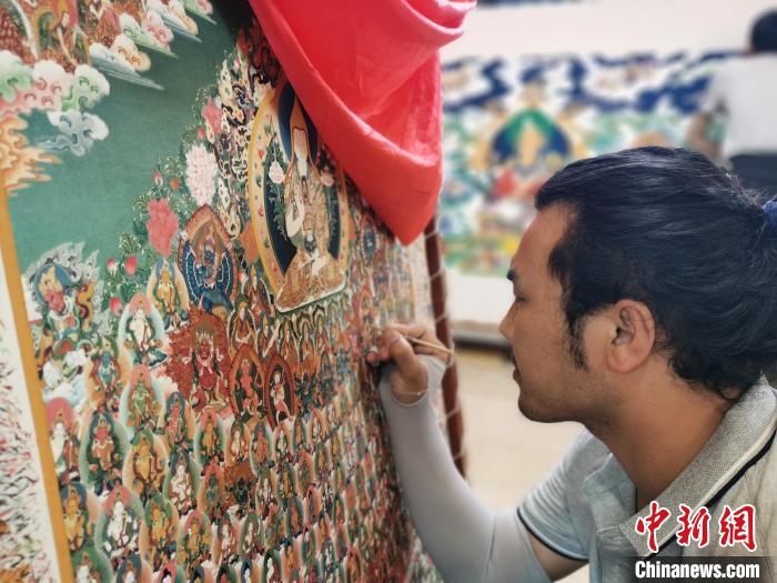 圖為更登才讓的徒弟繪畫唐卡?！?zhí)砀?攝